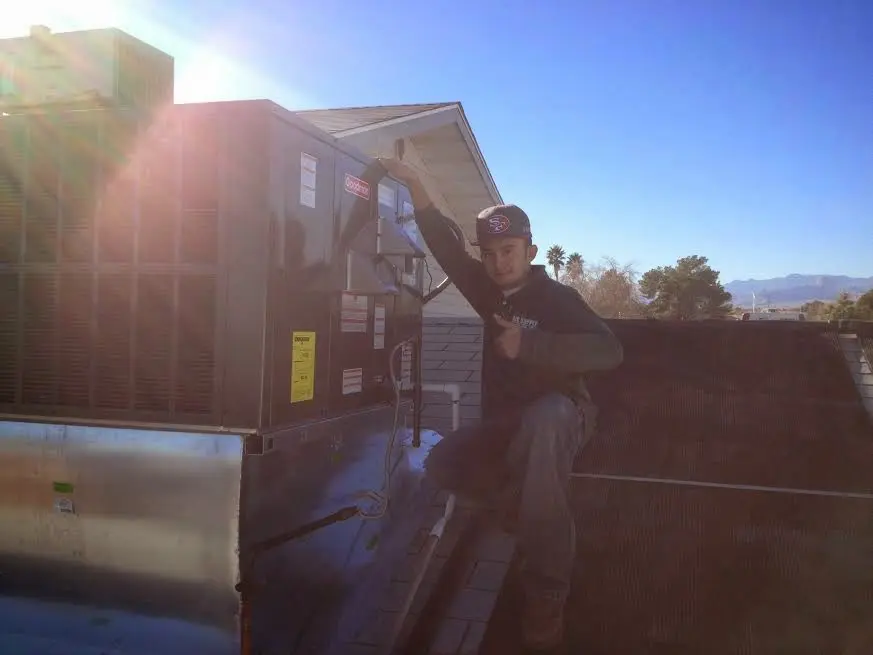 HVAC technician performing AC Tune-Up on a rooftop unit in Oceano
